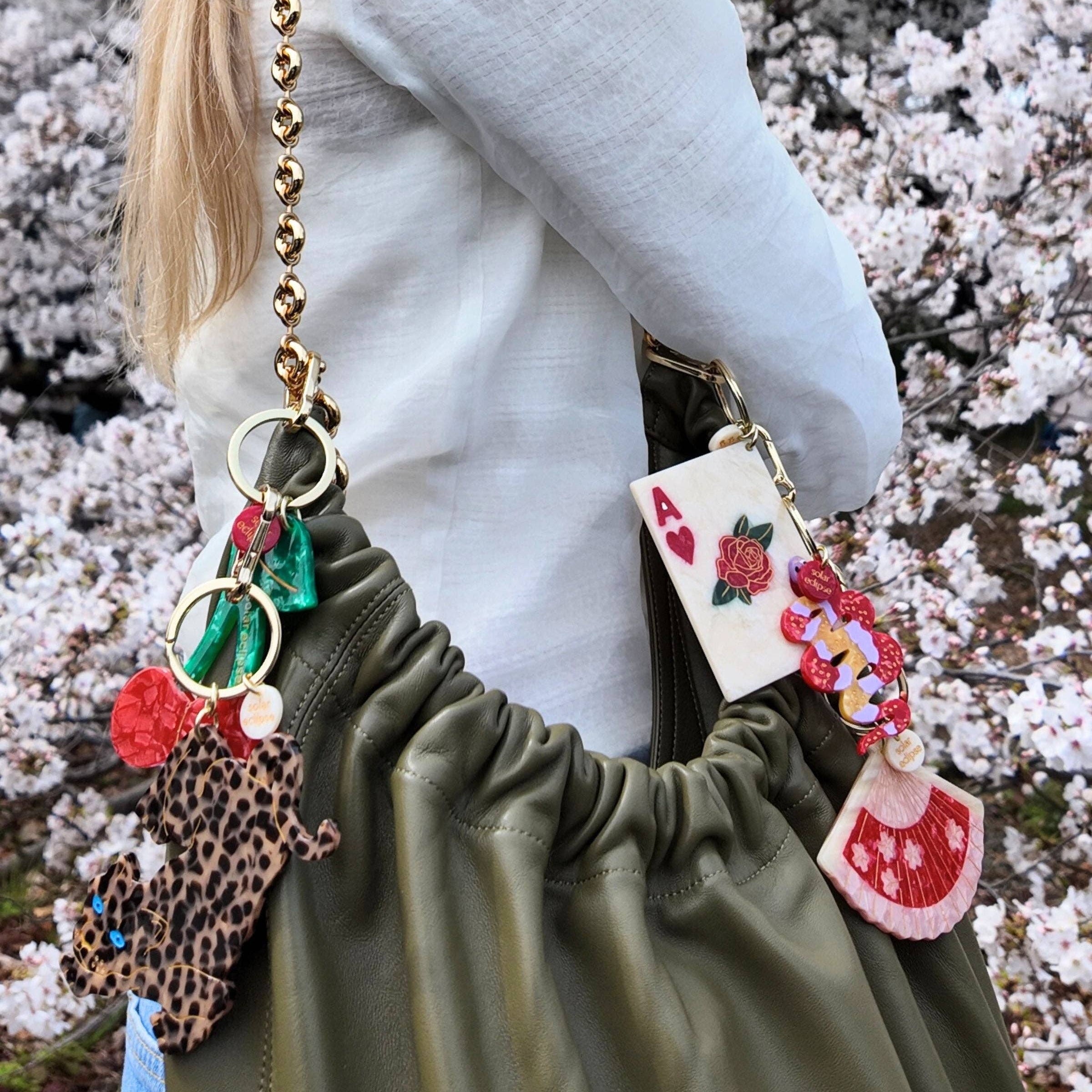 Person holding a bag with decorative keychains against a cherry blossom background
