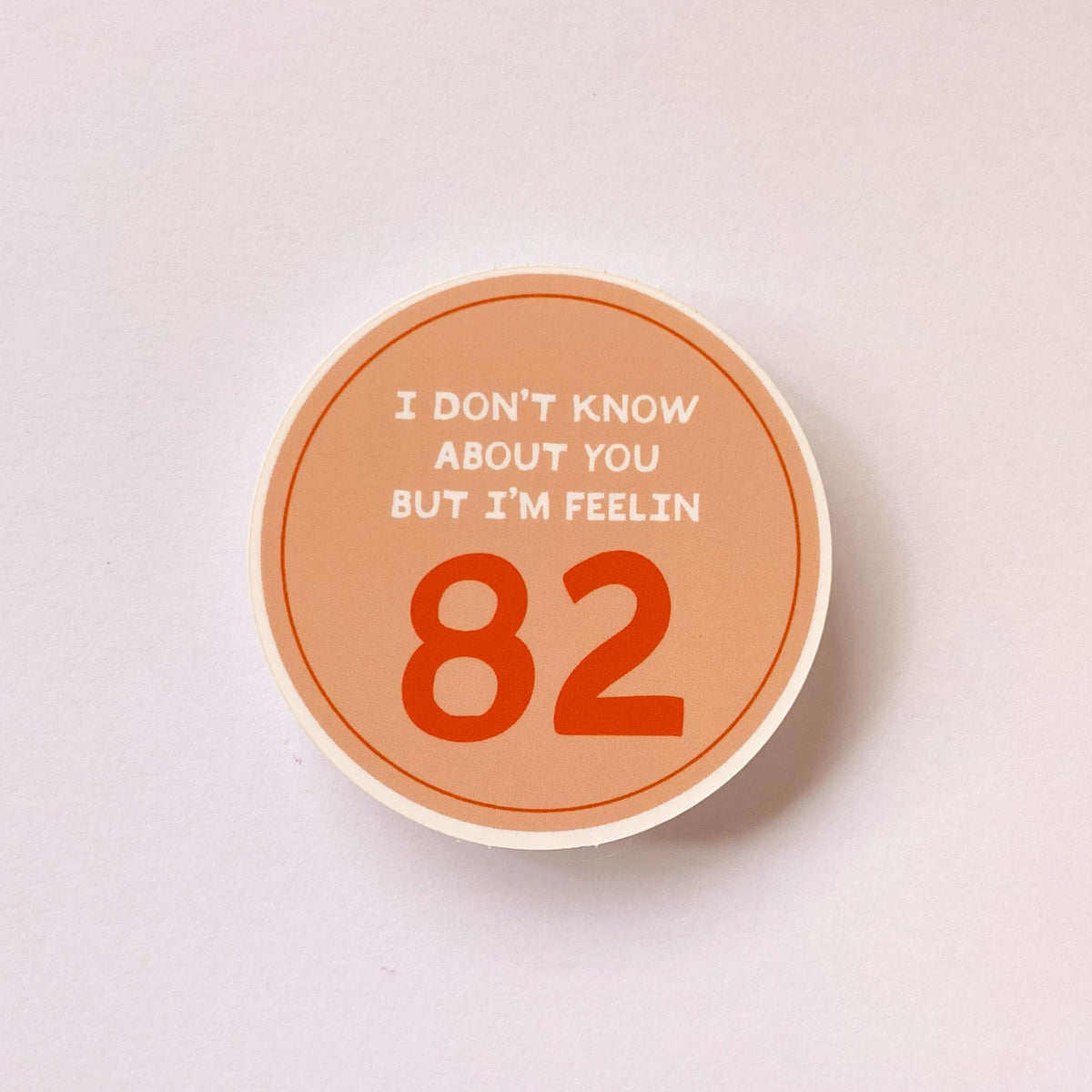 Circle orange sticker with words "I don't know about you, but I'm feeling 82".