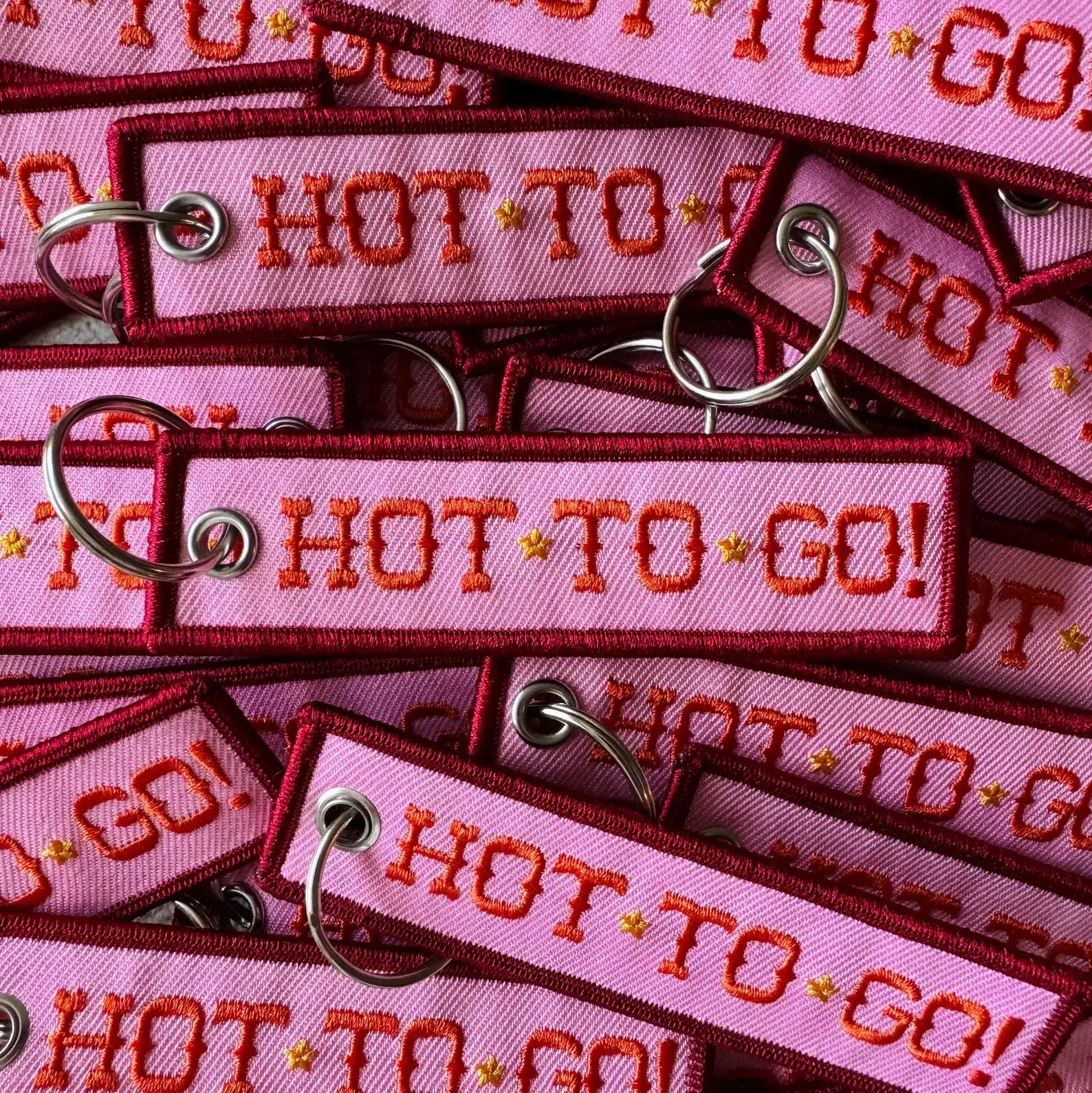 Pink keychains with 'HOT TO GO!' text on a pink background