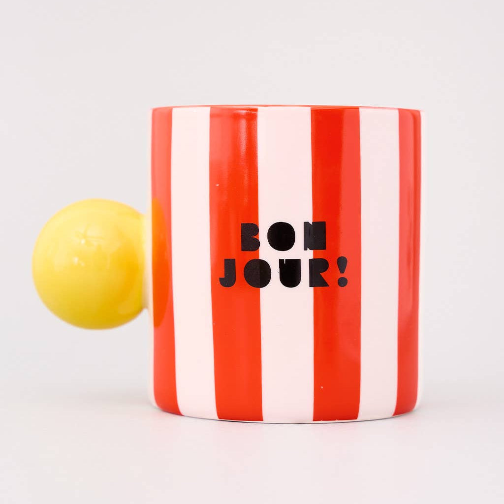 Striped mug with 'Bonjour!' text and a yellow object on a white background