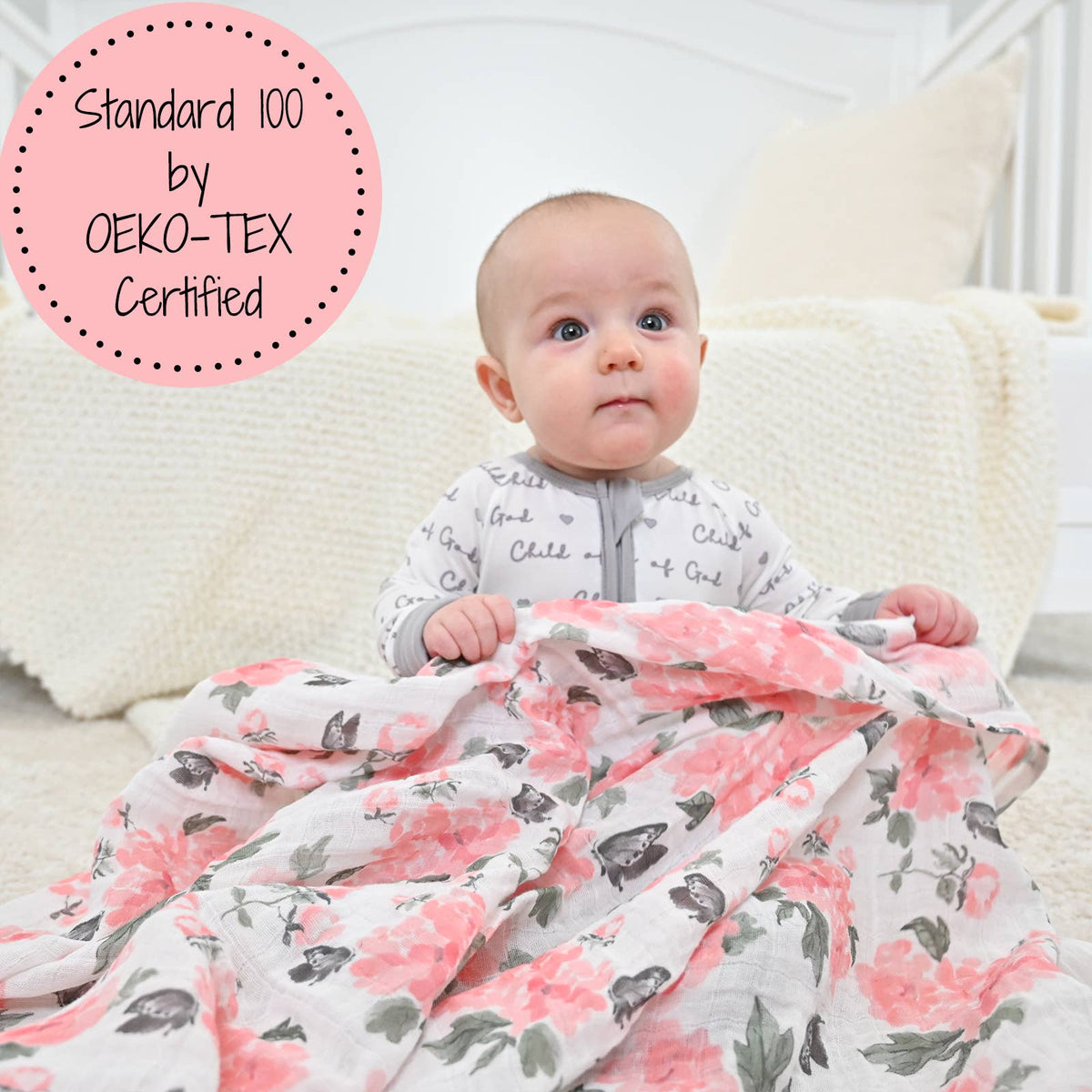 Baby wrapped in a floral blanket with 'Standard 100 by OEKO-TEX Certified' label.