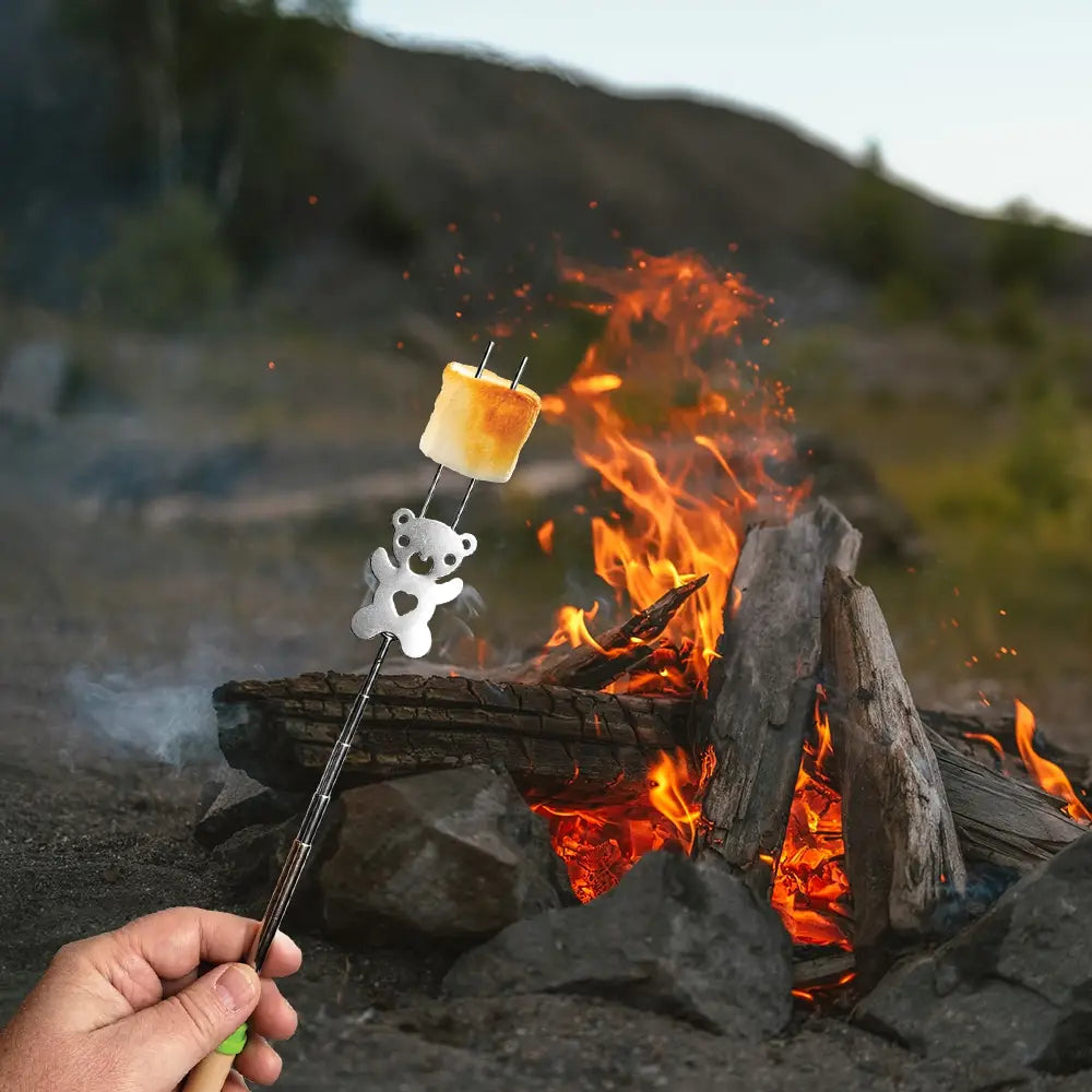 Marshmallow being roasted over a campfire with a teddy bear-shaped skewer