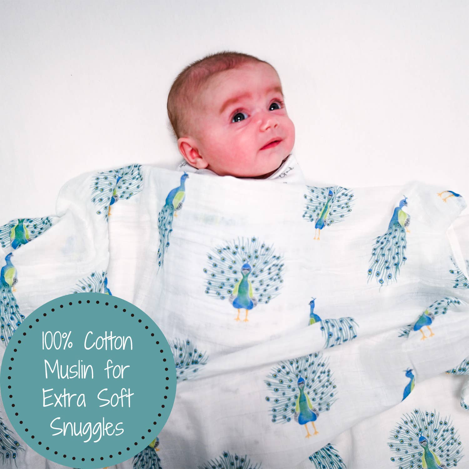 Baby wrapped in a white blanket with peacock patterns on a white background