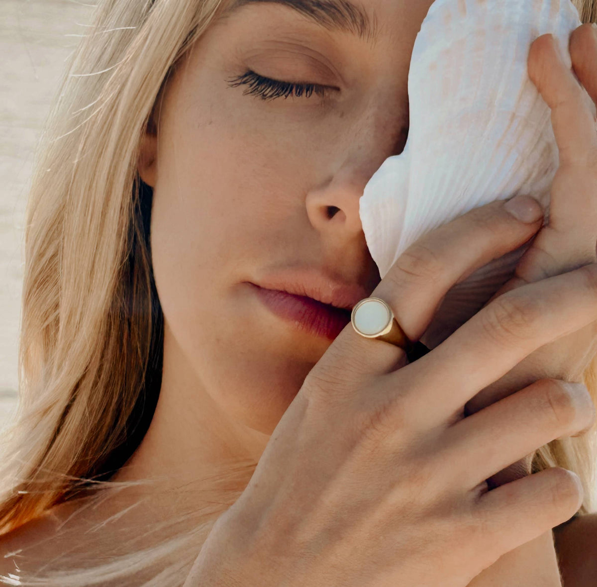 Woman holding a seashell to her ear, close-up shot.