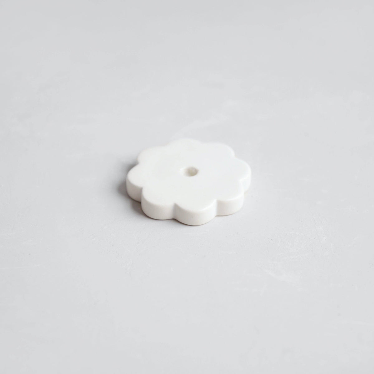 White ceramic flower-shaped object on a light gray background