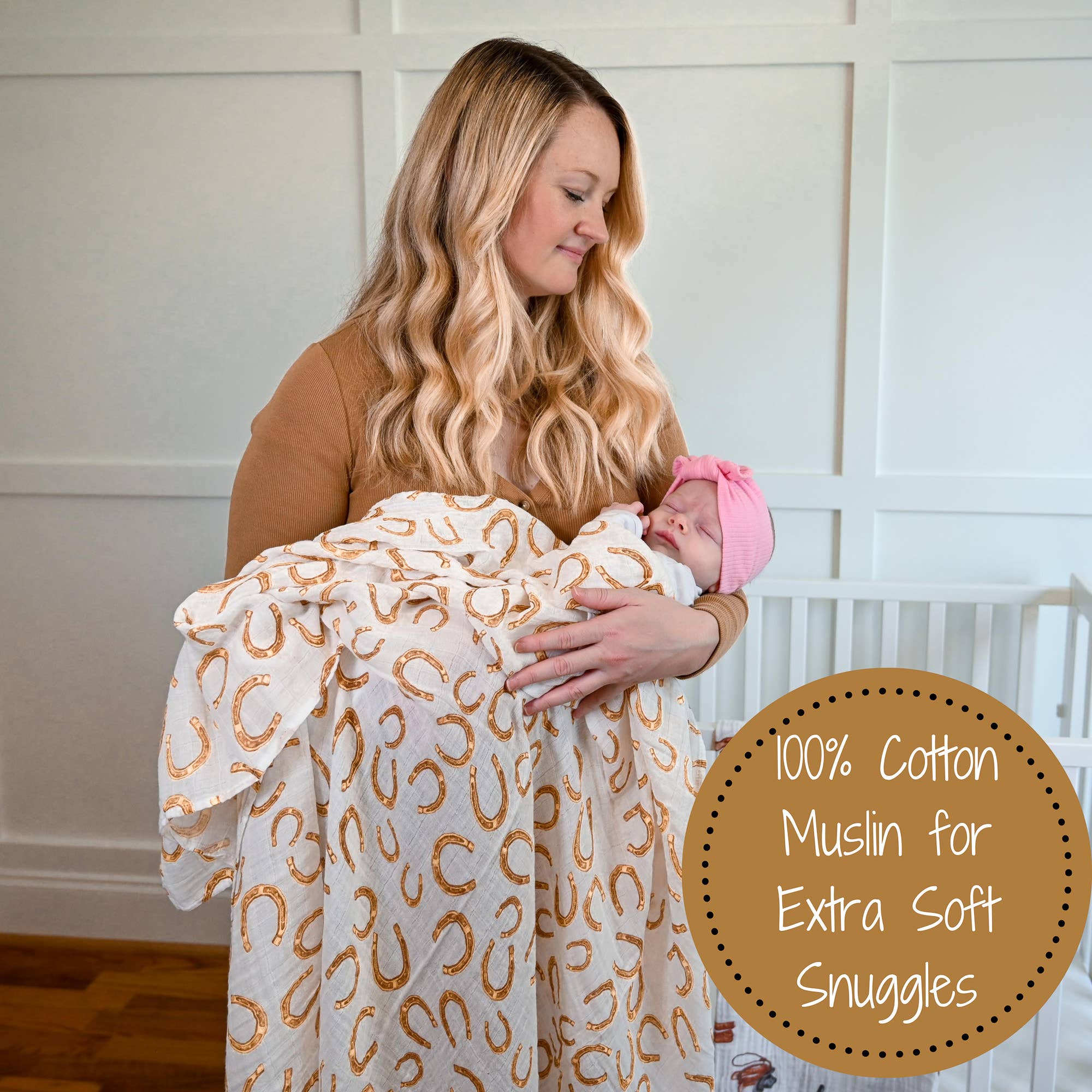 Woman holding a baby wrapped in a 100% cotton muslin blanket with a horse pattern.