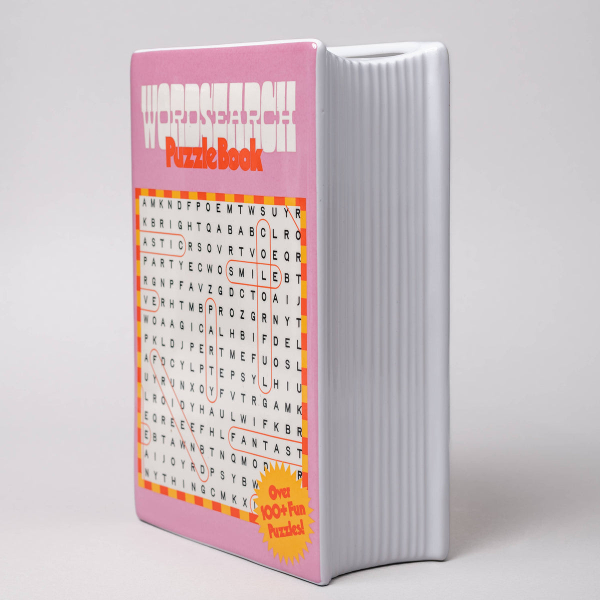 Pink puzzle book  vase with word search design on a gray background