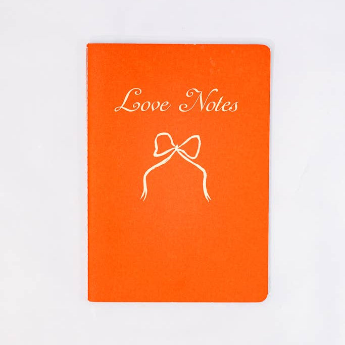 Orange notebook with 'Love Notes' and a bow design on a white background