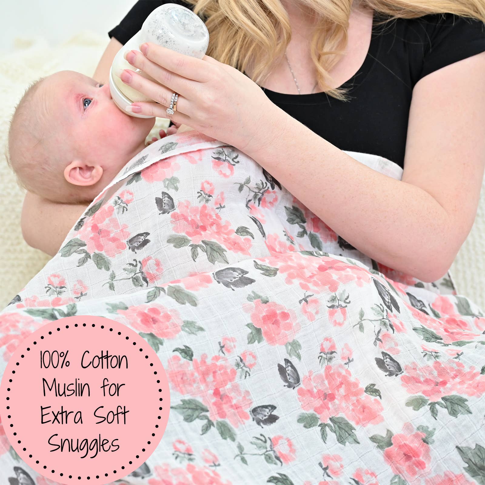 Woman feeding a baby with a bottle, wrapped in a floral blanket, with text about 100% cotton muslin.