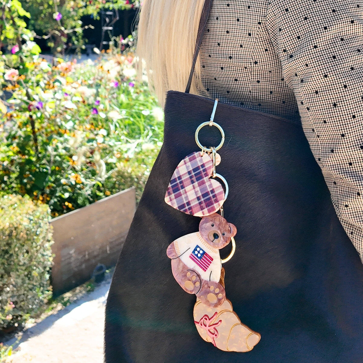 Person wearing a black apron with teddy bear keychains in an outdoor setting