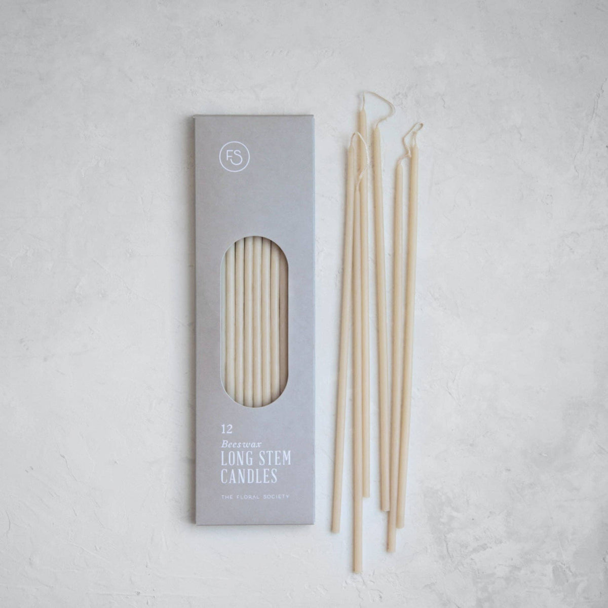 Set of long stem candles with packaging on a light gray background