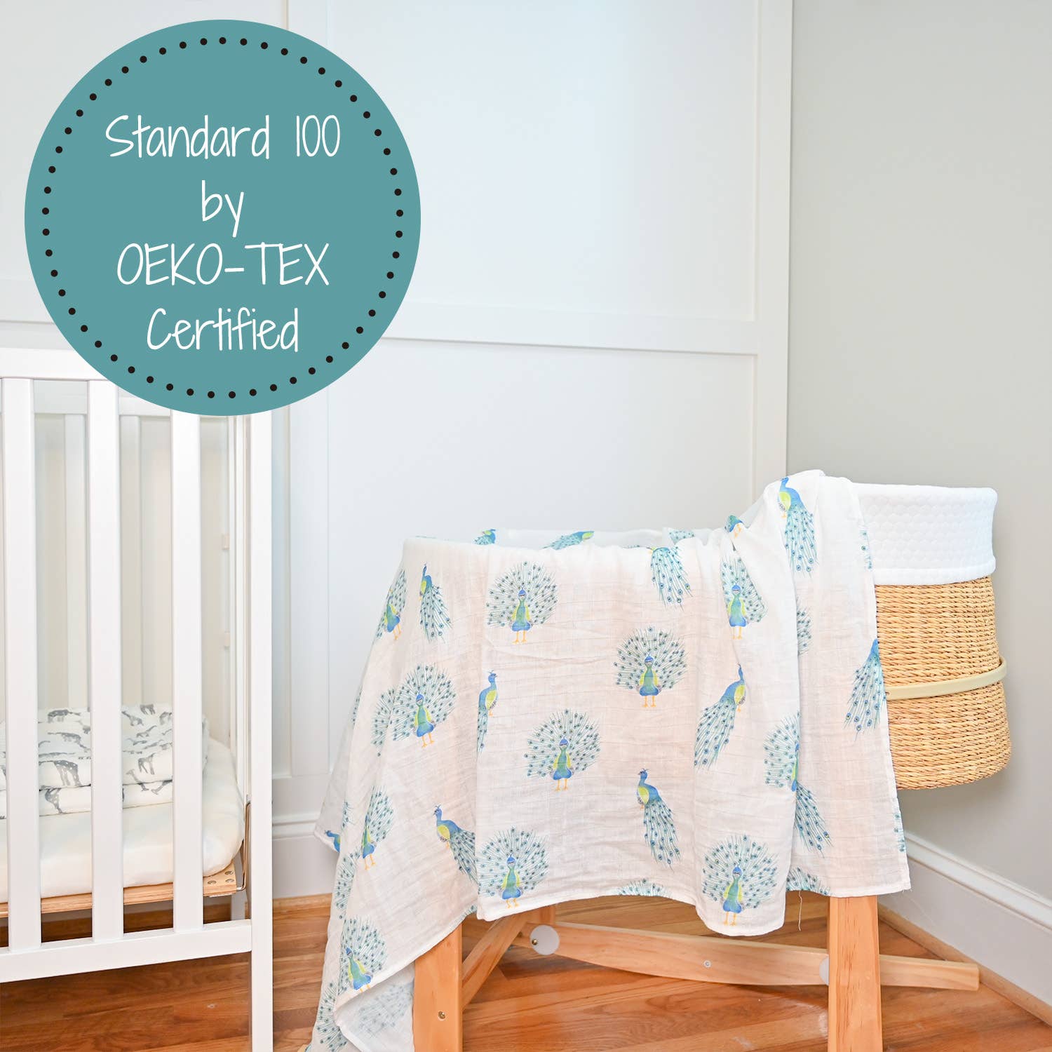 Baby crib with a patterned blanket draped over it, next to a wicker basket on a wooden floor.