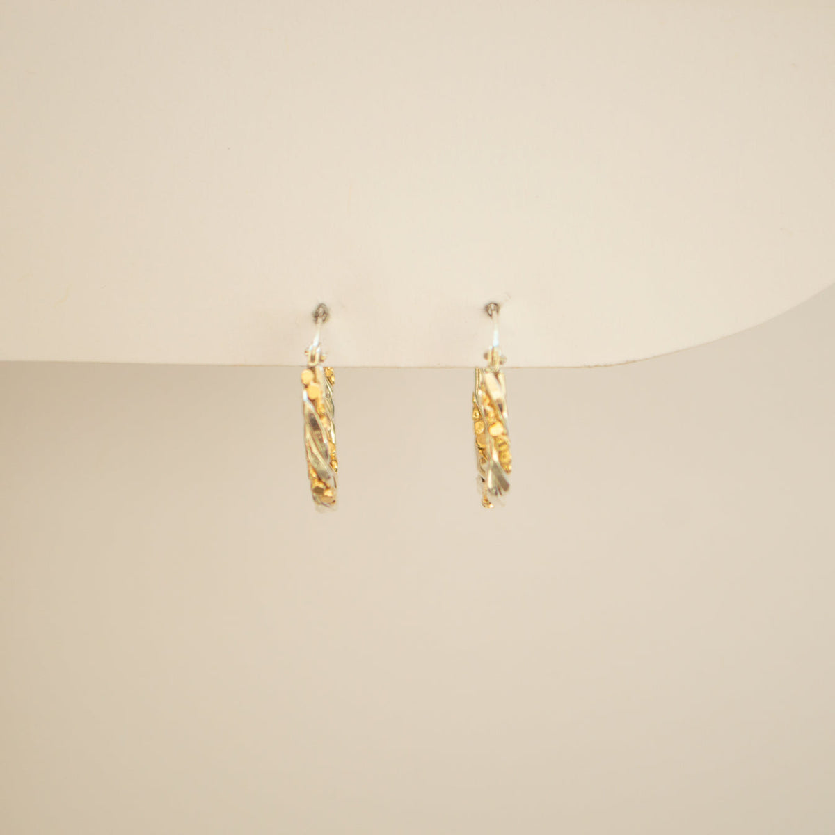 Hoops made from gold and silver twisted together, on an off white background. 