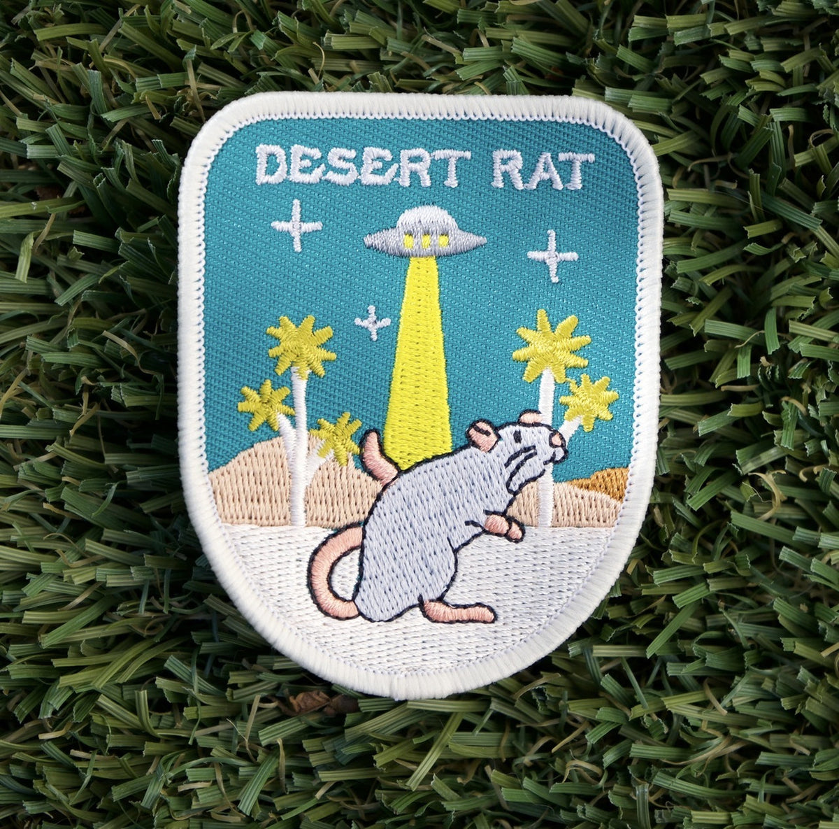 Iron-on patch with an embroidered rat and alien ship in a desert, with the words "Desert Rat".