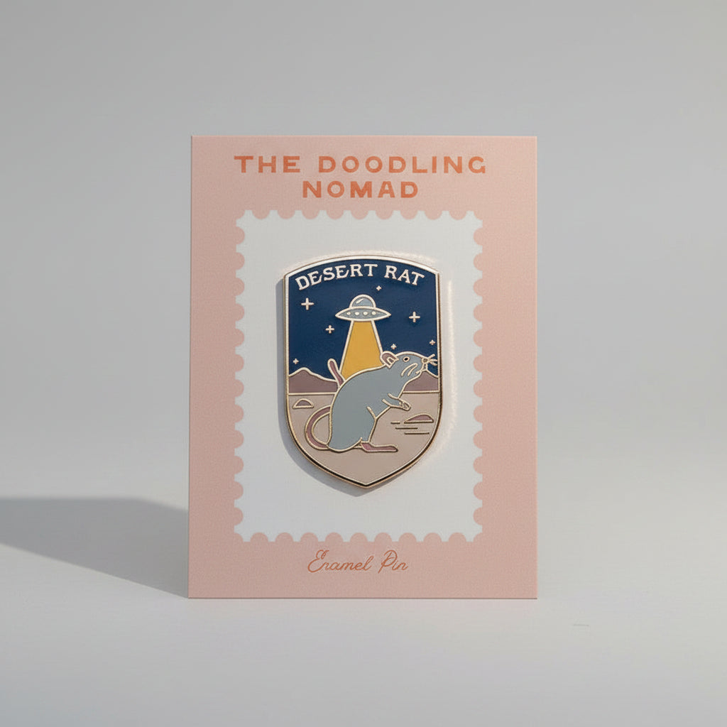 Enamel pin with a rat and an alien spaceship and the words "Desert Rat".