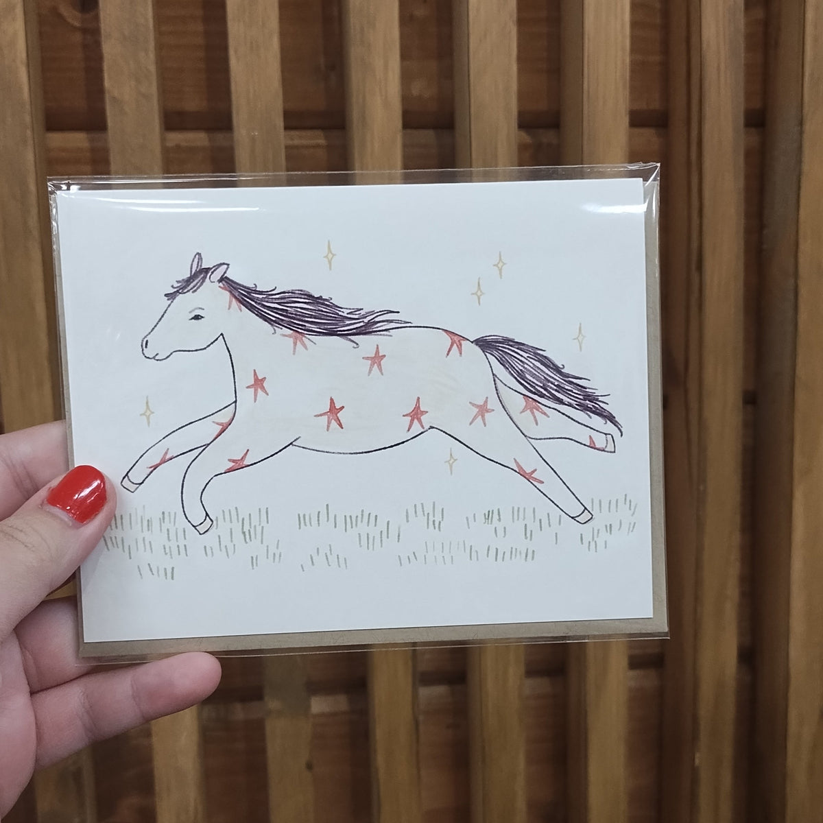 A card done in soft muted pastels. Horse with stars running through meadow with sparkles. 
