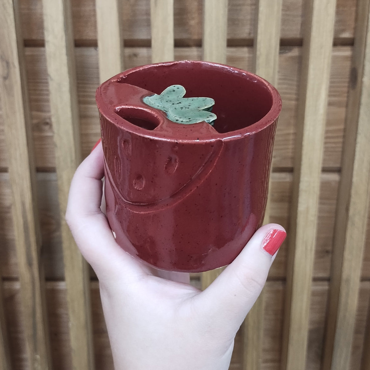 Deep red tumbler with a leafy green mouth piece. 