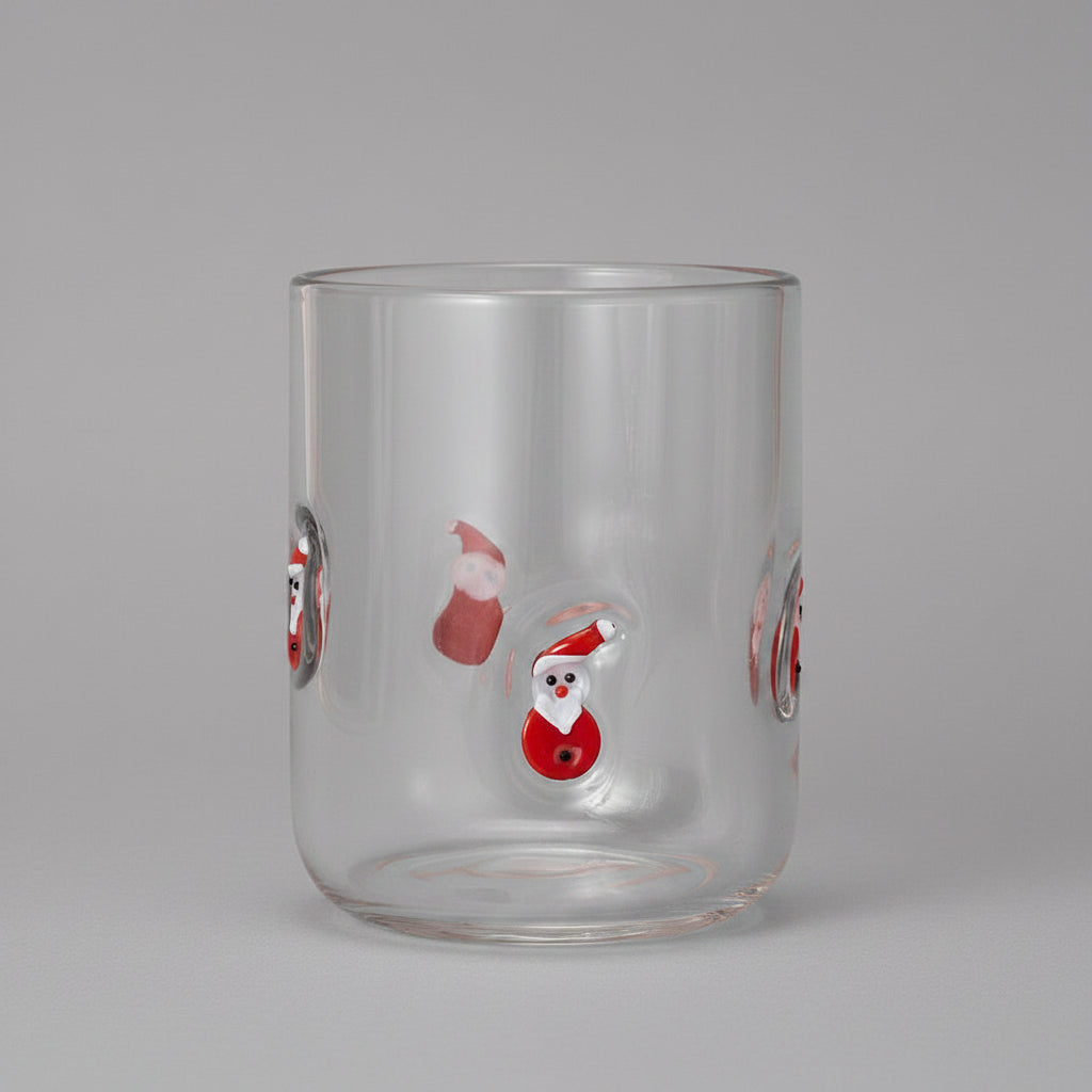 Clear glass tumbler with Santa Claus designs on a red background