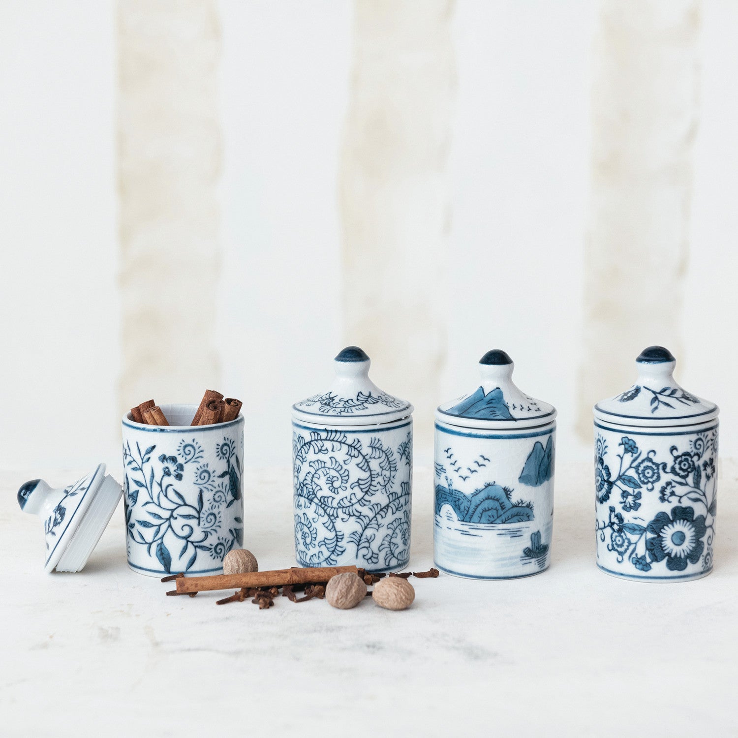 Handcrafted stoneware spice jar that brings artisanal charm to your kitchen. Each jar features a unique hand-stamped pattern with beautiful crackle glaze in classic blue and white tones. Measuring 2-1/4" round by 4-1/4" tall, it's the perfect size for storing your favorite spices, herbs, or small pantry staples. Available in 4 distinct styles—each one truly one-of-a-kind due to the hand-crafted nature of the piece. The rustic glaze and organic variations make every jar special, adding warmth and character.