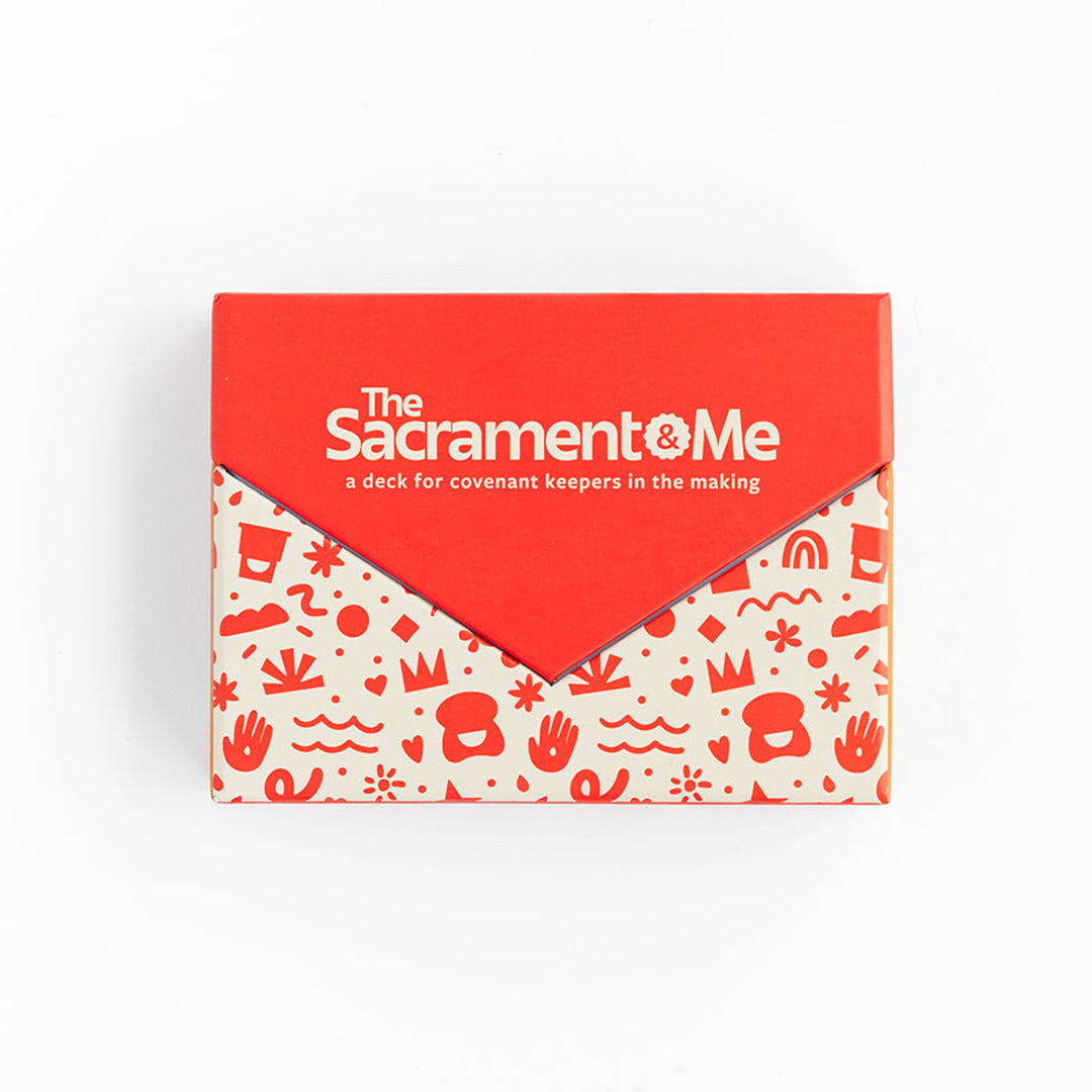 A red and cream card deck box features the title “The Sacrament & Me” and the subtitle “a deck for covenant keepers in the making.” The lower portion is decorated with a playful red pattern of hearts, crowns, flowers, hands, and other symbols. 
