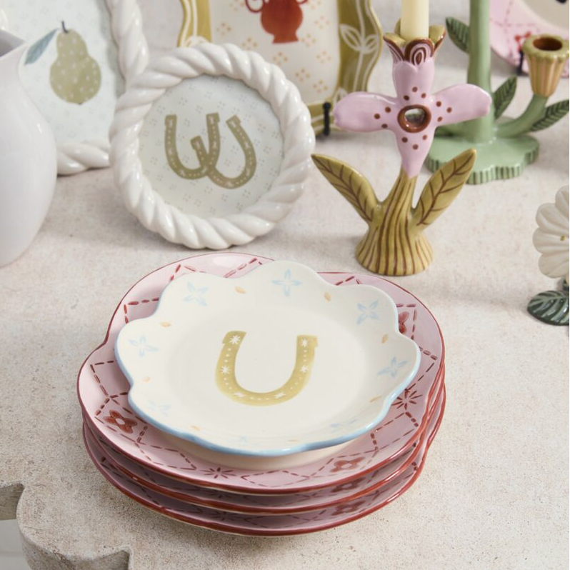 Set of ceramic plates with letter 'U' horse shoe design on a decorative surface