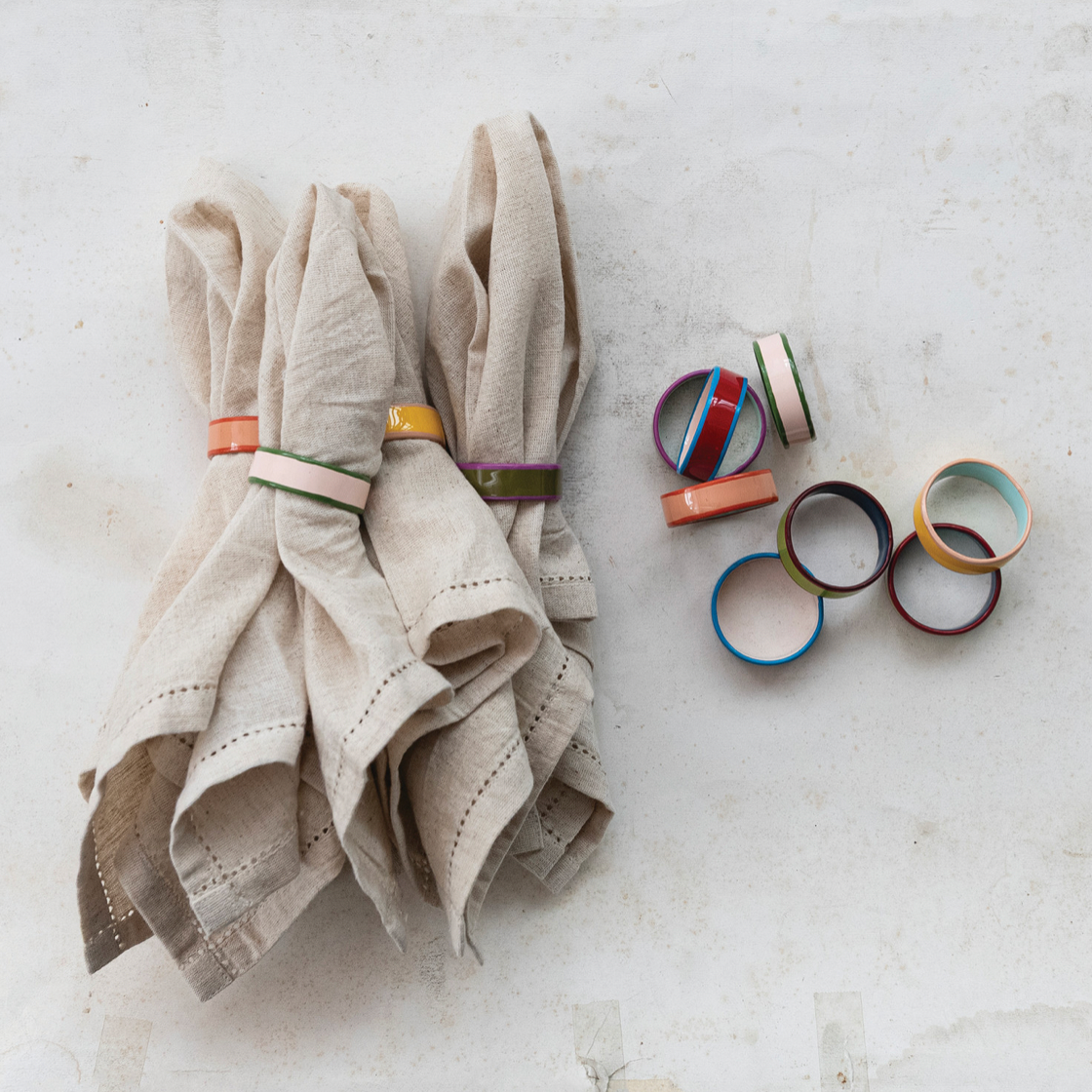 Beige napkins with colorful napkin holders on a light gray surface