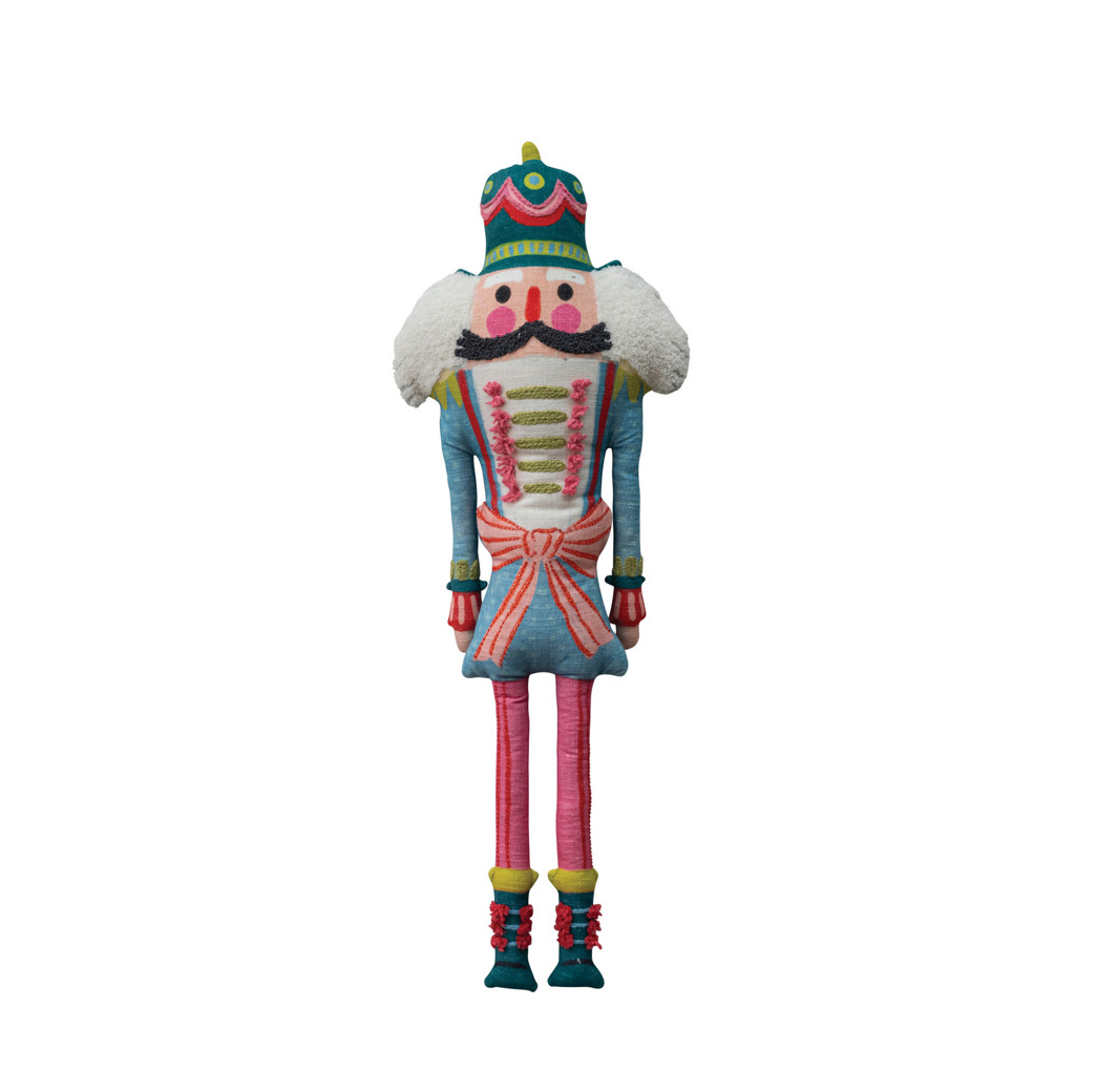 A colorful plush nutcracker doll with a blue jacket, pink pants, green and red accents, and a white fluffy beard, isolated on a white background.