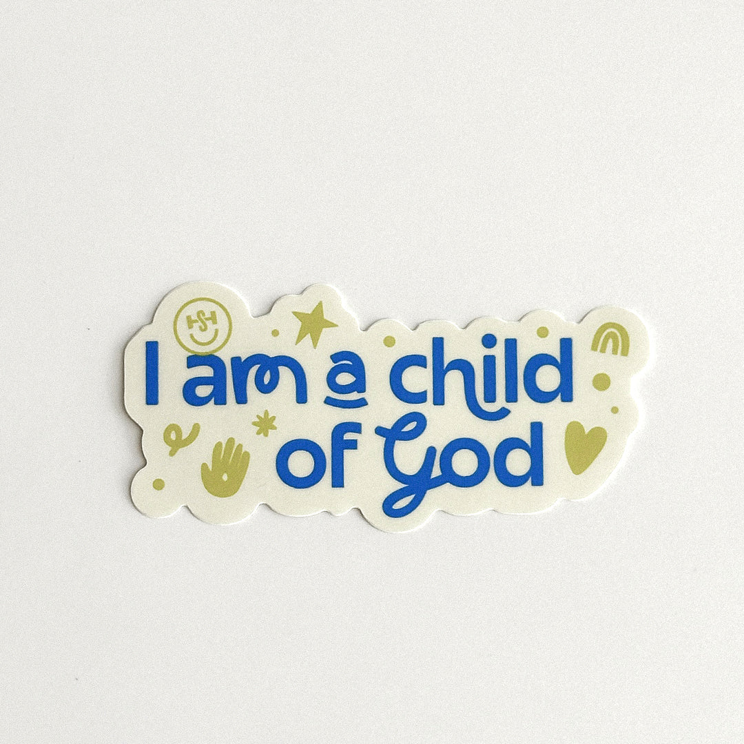 A cream-colored sticker features bold blue lettering that reads “I am a child of God,” surrounded by playful olive-green stars, hearts, dots, and hand-drawn symbols. The sticker has a scalloped, irregular shape and a cheerful, colorful design.