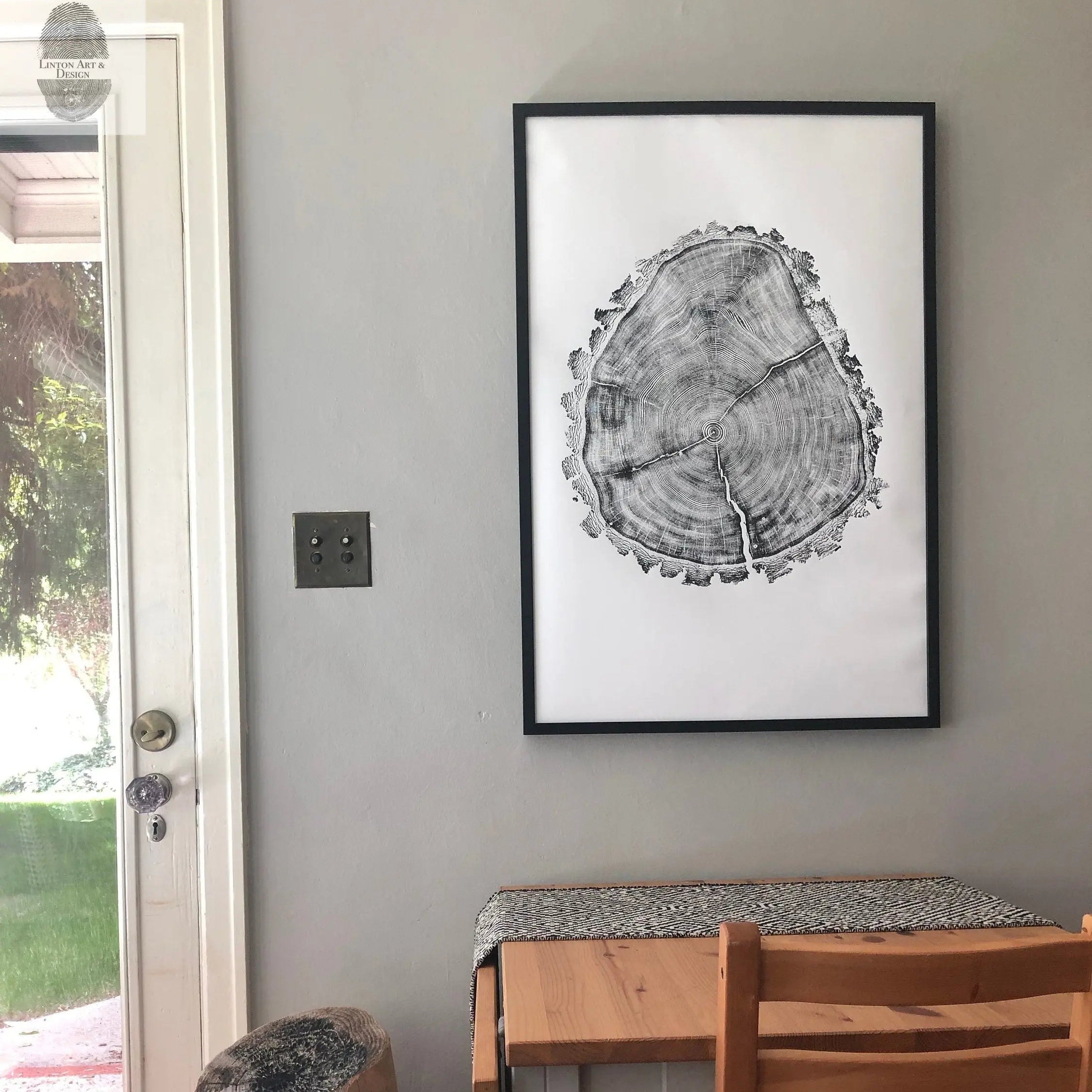 Dining area with wooden table and chairs, framed black and white artwork on the wall.