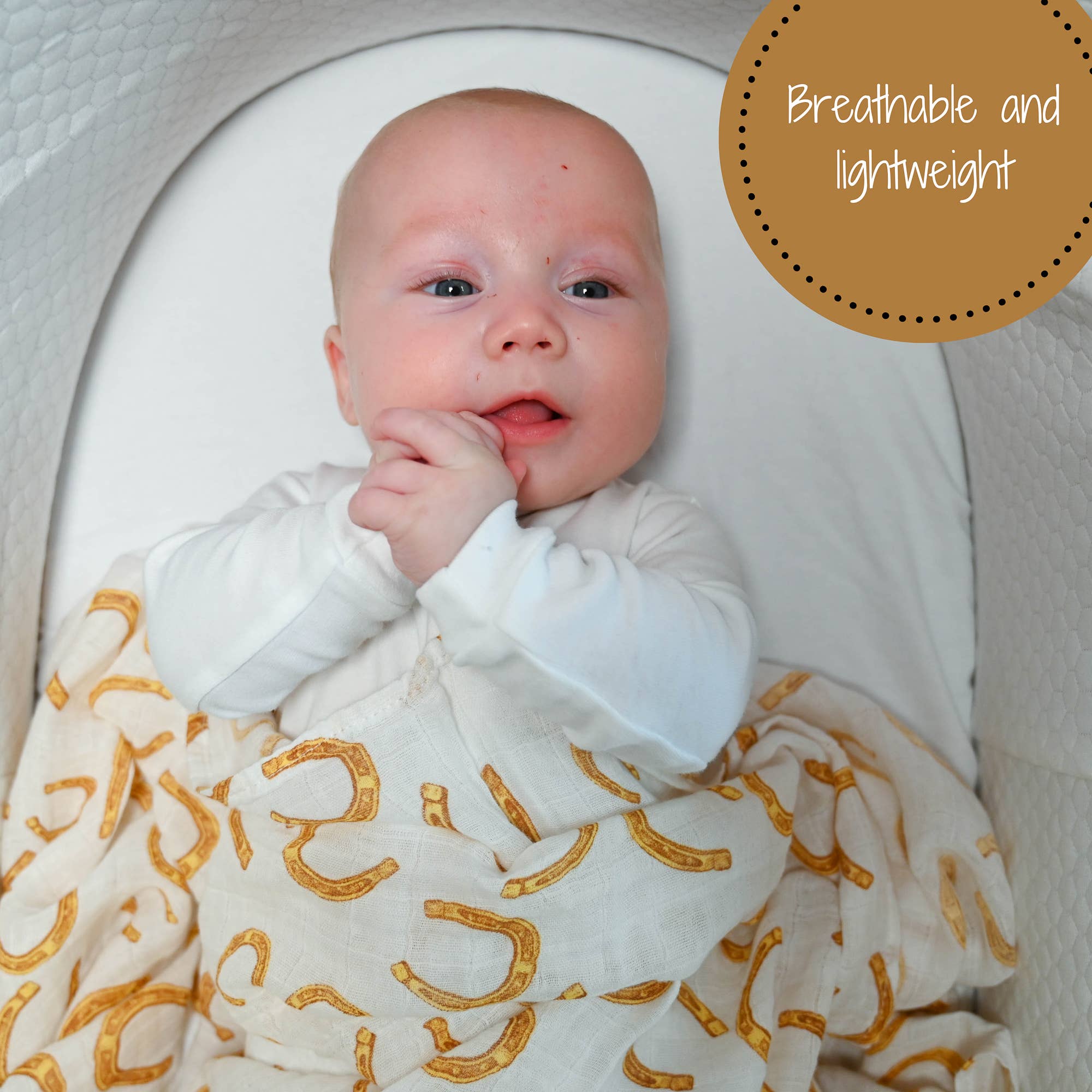 Baby wrapped in a white blanket with gold patterns, sitting in a crib.