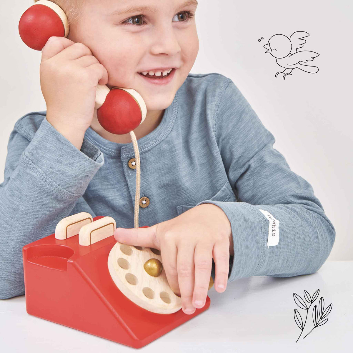 Child playing with a red toy phone against a plain background