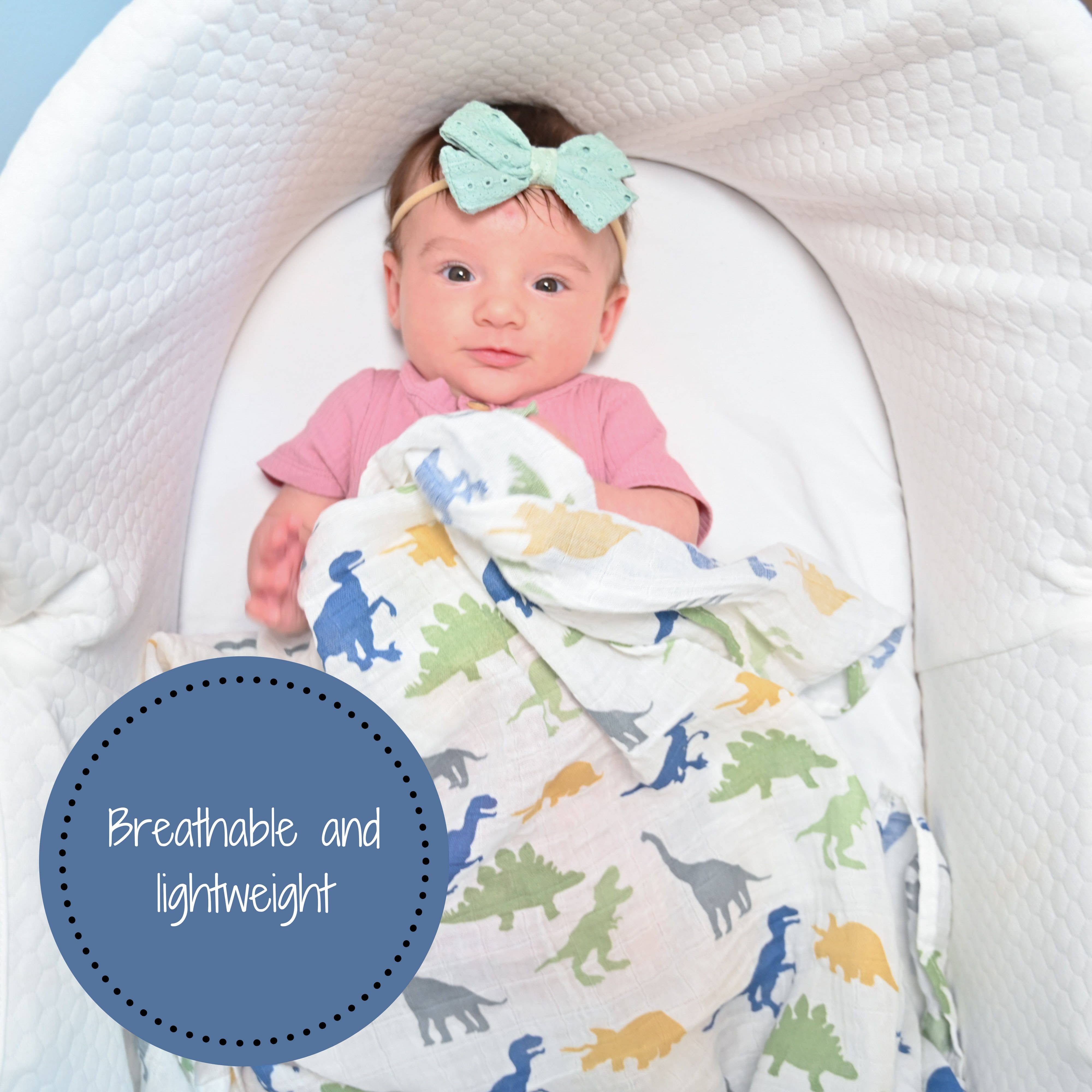 Baby wrapped in a dinosaur-patterned blanket with a headband, sitting in a crib.