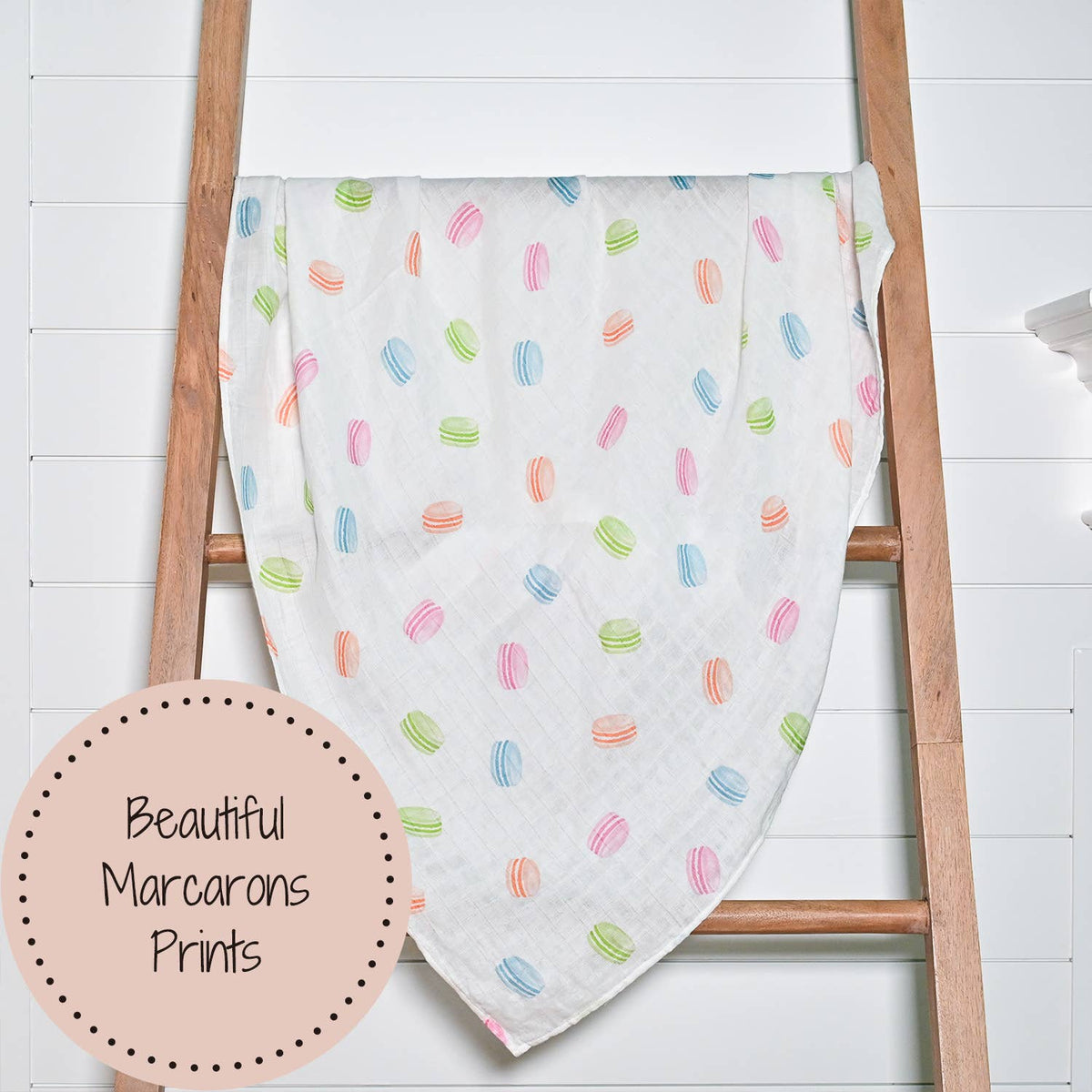 Baby blanket with colorful marcarons pattern draped over a wooden ladder on a white background.