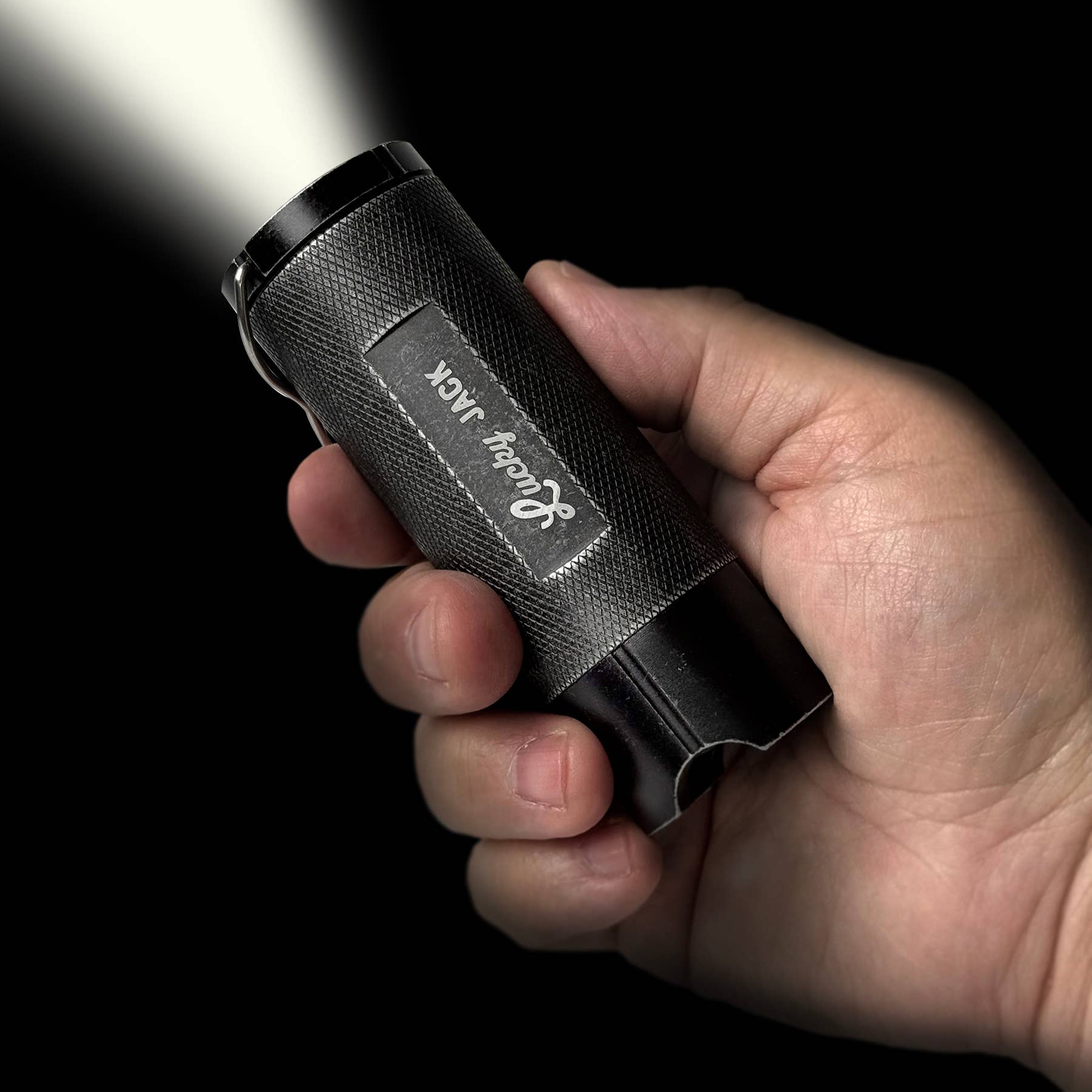 Hand holding a black flashlight with 'Randy Max' branding against a dark background