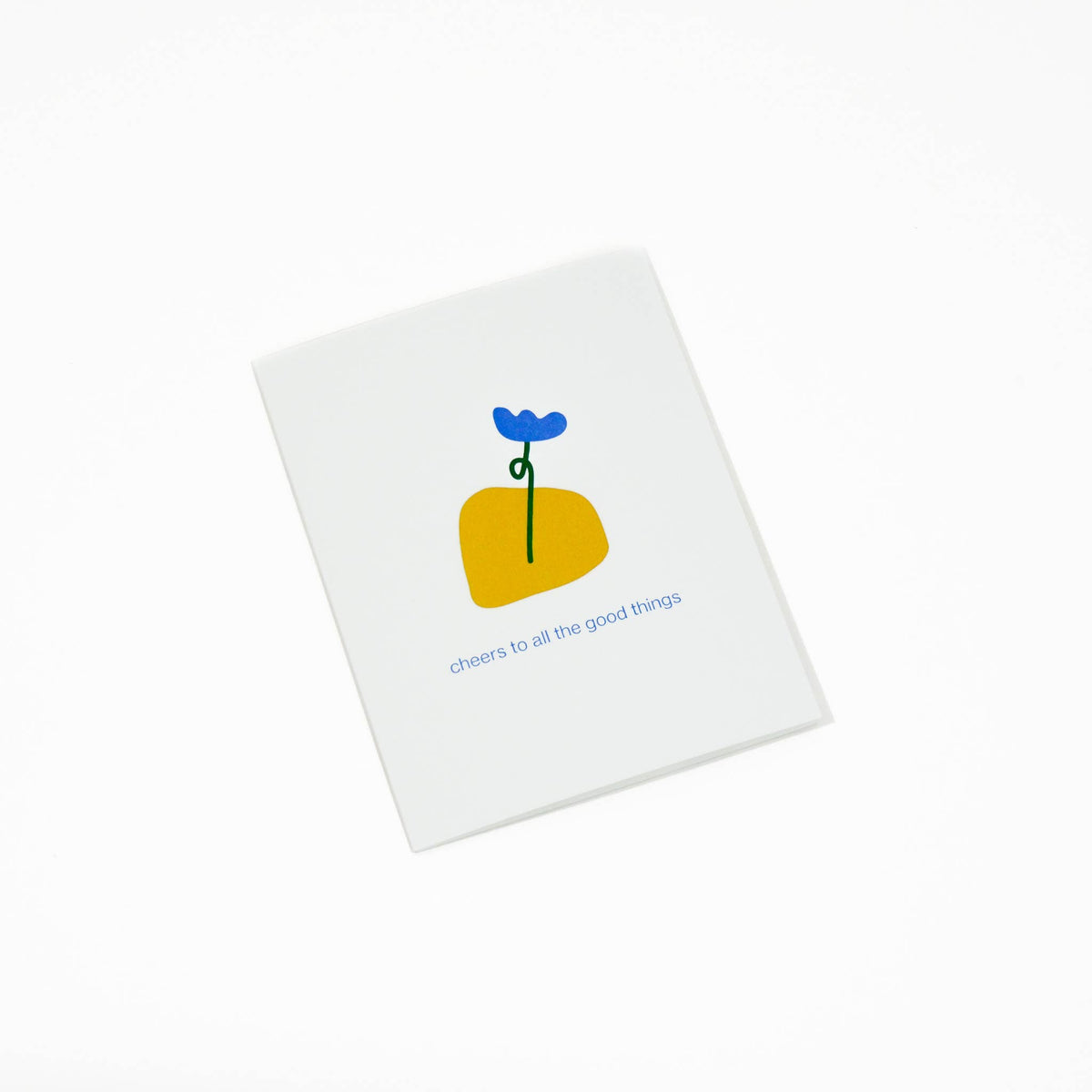 A white  greeting card with a minimalist illustration of a yellow flower with a blue bloom and the text 'cheers to all the good things' printed below, shown on a clean white background.