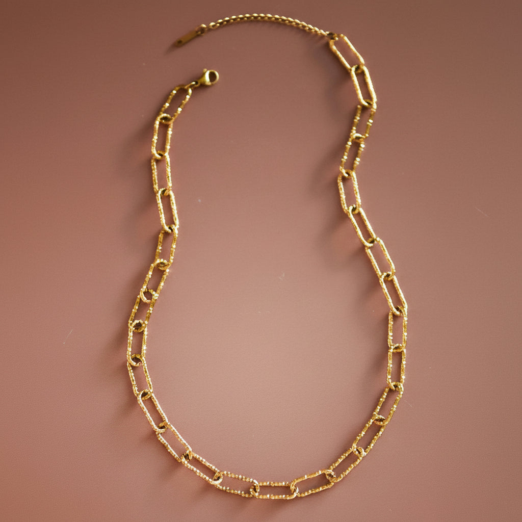 Elevate your everyday style with this 18K gold dipped stainless steel chain necklace, featuring a textured large paperclip design. Crafted from hypoallergenic stainless steel, it's waterproof and tarnish-resistant for lasting wear. The luxe gold plating maintains its brilliant shine when kept away from lotions, perfumes, and harsh chemicals. Perfect for layering or wearing solo, this versatile piece transitions seamlessly from day to night.