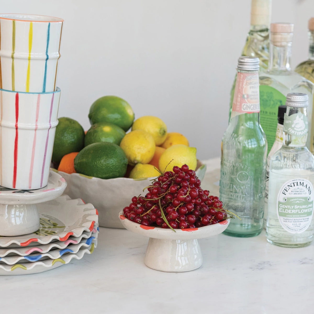 Add a splash of charm to your table with this Hand-Painted Stoneware Pedestal featuring a delightful pink flower &amp; green leaf design. Perfect for showcasing desserts or elevating your favorite treats, its sturdy stoneware build combines beauty and function. Brighten up any gathering with this playful centerpiece that’s as practical as it is pretty!&nbsp;5" Round x 2-1/2"H