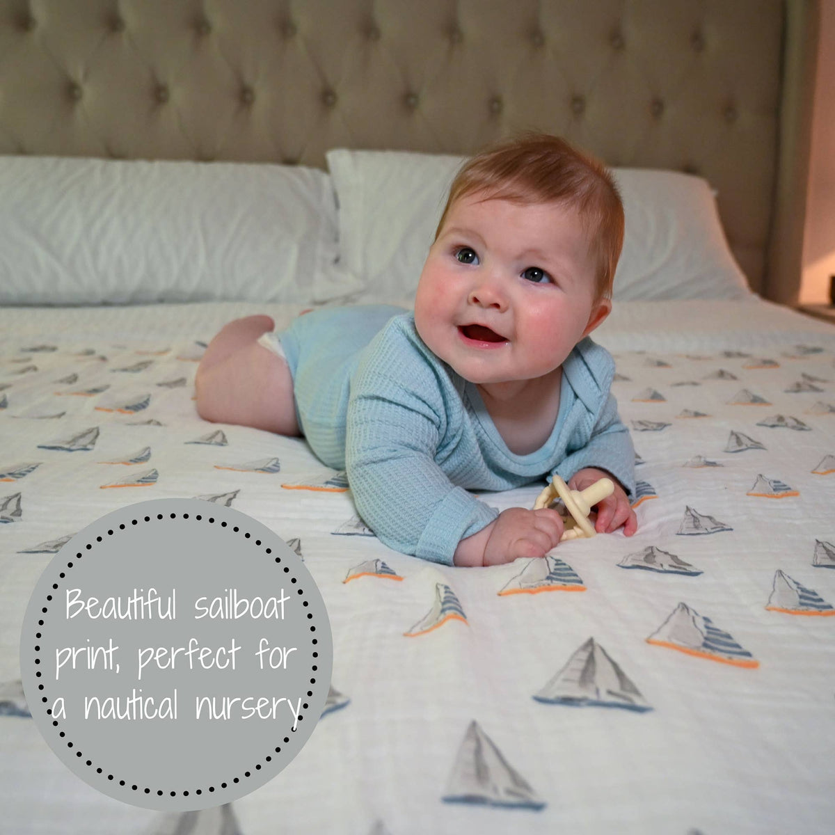 Baby lying on a bed with a sailboat patterned blanket
