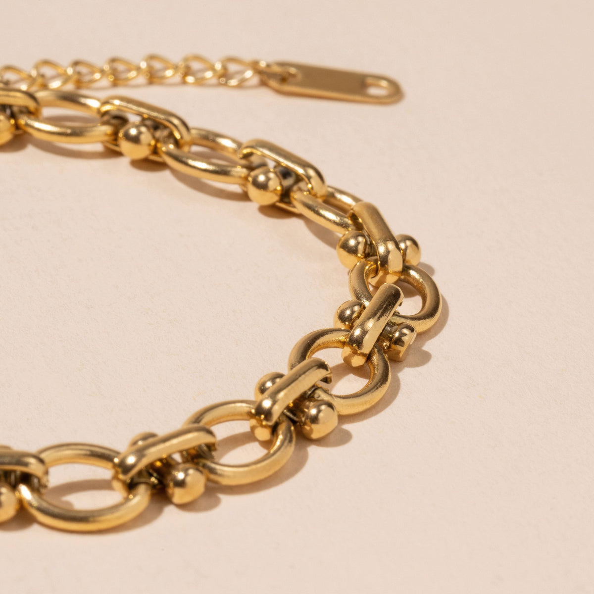 Gold chain bracelet on a beige background