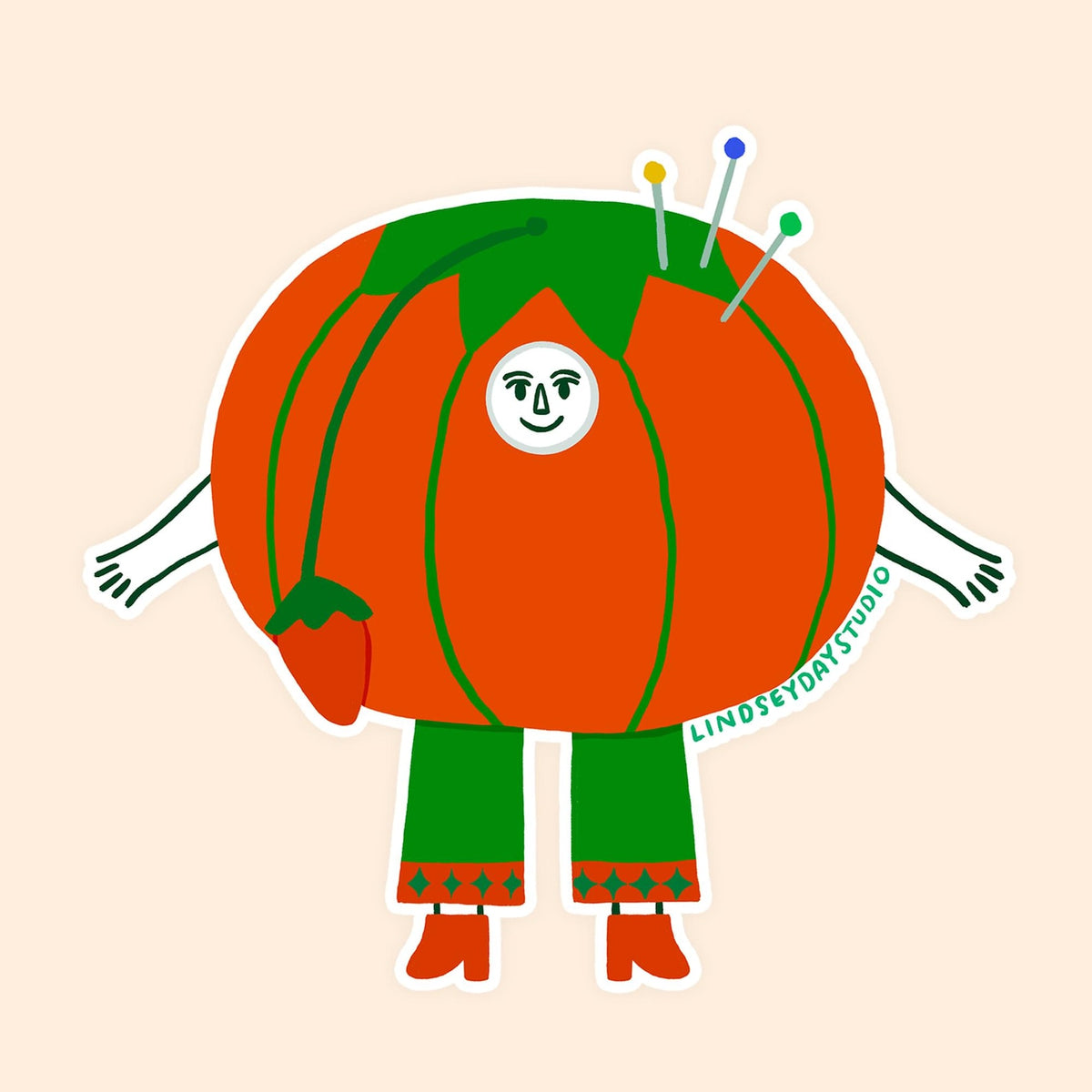 Red sewing tomato with green accents. Pins stick out, sticker has a face, arms and legs. 