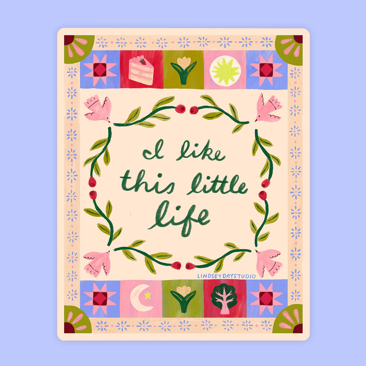 Cream sticker with blocks of color, and a wreath of green surrounding cursive words "I like this little life". 