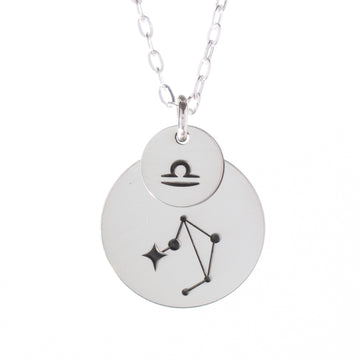 A sterling silver necklace with two layered pendants, one featuring a zodiac sign and the other a constellation, suspended on an 18-inch chain.